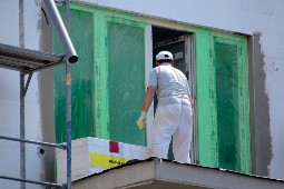 Eine Person von hinten, bei Sanierungsarbeiten an den Fenstern, zu sehen.