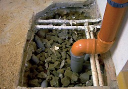 Foto einer punktuellen Unterboden-Absaugung. Rohrsystem aus Kiesboden unter dem Fundament heraus.